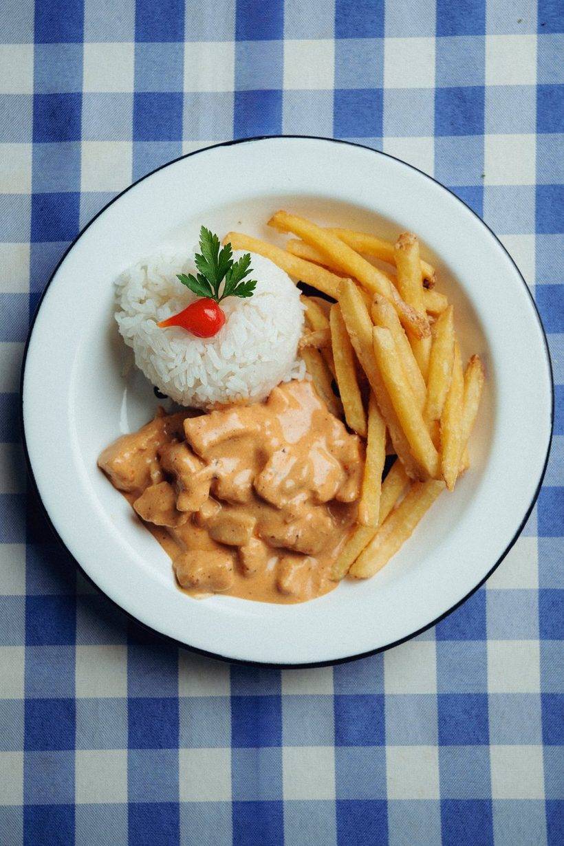 Strogonoff com arroz e batata frita no prato branco