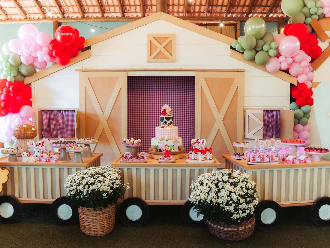 Mesa de bolo e doces montada no celeiro, com arco de balões