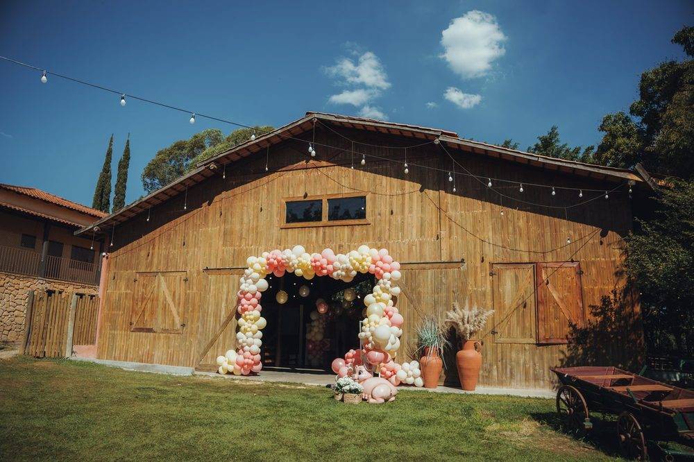 Fachada do Celeiro Clássico com arco de balões em tons de rosa e luzinhas