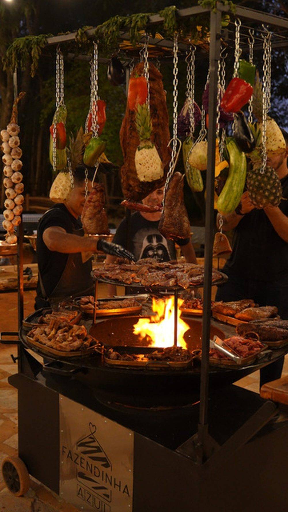 Espetos de carne e legumes assando no fogo de chão