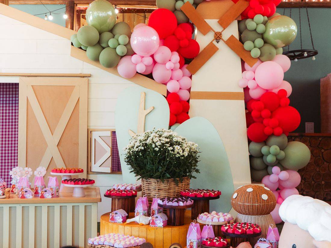 Mesa de doces com arco de balões e o moinho ao fundo