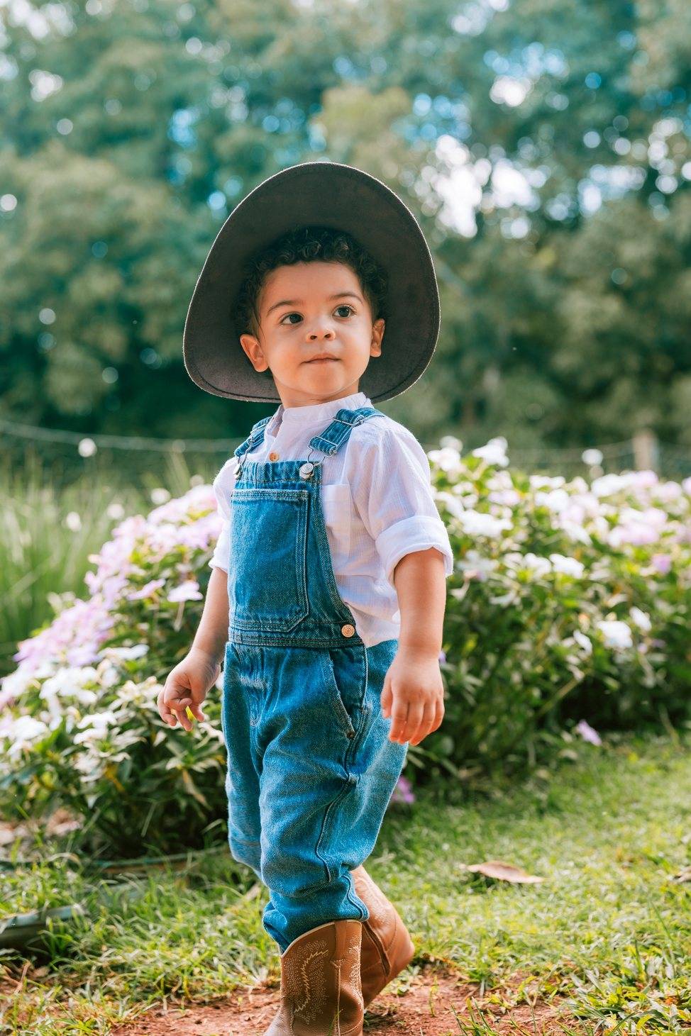 Menino de jardineira e chapéu no jardim
